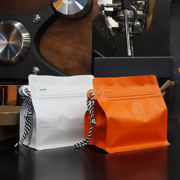 Sacs de café blanc et orange de 150g avec vue avant en porte-badge