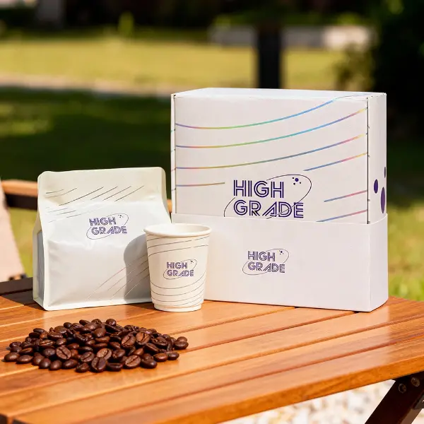 Boîte à café personnalisée de marque avec sachet à café assorti et gobelet en carton exposés à l’extérieur sur une table en bois