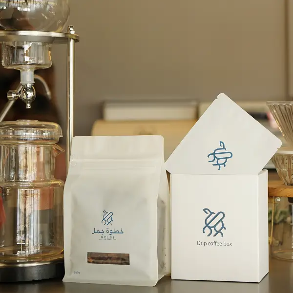 Boîte en carton et sachet de café personnalisés premium présentés dans un environnement de café pour l’affichage de la marque
