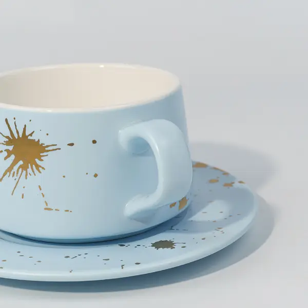 Détail du manche de tasse à café en céramique avec décoration éclaboussée de feuilles d’or