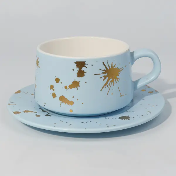 Vue latérale d’une tasse à café en céramique en feuille d’or avec un motif de projections peint à la main