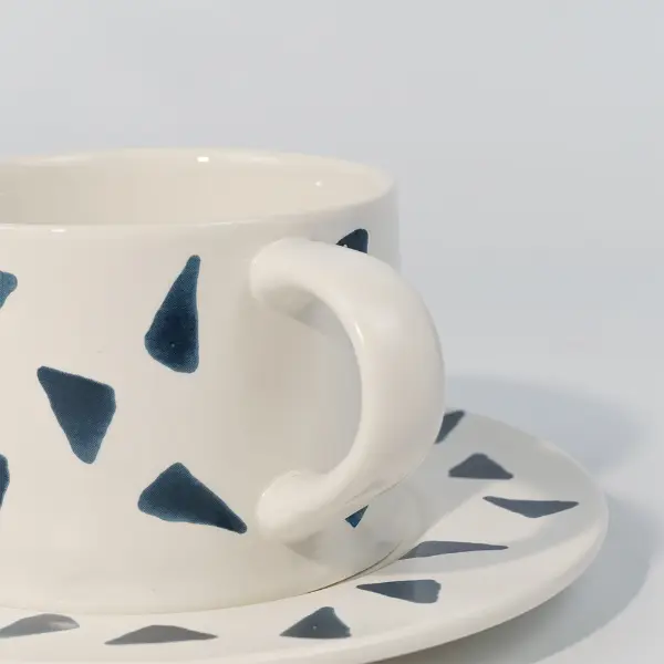 Gros plan de la poignée sur une tasse à café en céramique imprimée avec imprimé décoratif