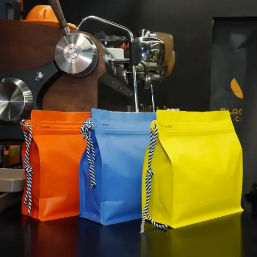 Les sacs à café personnalisés avec porte-cordon ne sont plus un format de niche dans 2026. Ils sont devenus un outil pratique, Choix d’emballage à grand volume pour les grains en vrac et le café moulu—surtout lorsque les marques ont besoin à la fois de solidité opérationnelle et d’un nettoyage, Un look prêt pour le commerce. At YPAK, Nous traitons le cordon comme plus qu’une simple sangle. Utilisé correctement, cela devient un point de manipulation fonctionnel et un signal visuel de durabilité, ce qui peut influencer la façon dont les acheteurs jugent la qualité en quelques secondes. L’emballage en vrac présente un défi constant: Il doit travailler dur dans l’arrière-salle, mais elle représente tout de même la marque en visibilité. Cela signifie stabilité, Refermeture fiable, Gestion du gaz, et la commodité de la manipulation. Quand ces éléments se combinent, Le sac cesse d’être « juste un emballage » et commence à agir comme un outil qui protège la fraîcheur, Accélère le flux de travail, et garde les présentoirs bien rangés. Pourquoi ce format l’emporte dans 2026 Emballage en vrac Les acheteurs en vrac sont pratiques. Ils veulent moins de problèmes et une gestion plus rapide. Mais même en gros, Les décisions sont toujours prises rapidement. Un sac qui tient debout et semble cohérent témoigne du professionnalisme. Un sac qui s’affaisse, rides, ou que c’est gênant de porter un signal de risque. La structure à fond plat est l’une des raisons pour lesquelles ce format gagne en popularité. Il offre une meilleure stabilité sur les étagères, dans les réserves, et dans les installations de torréfaction où les sacs peuvent être déplacés quotidiennement. La deuxième raison est le cordon latéral renforcé. Quand un sac est lourd, Les équipes ont besoin d’un point de préhension prévisible. La corde réduit la tension lors du levage, supports suspendus lorsque l’espace est limité, et rend les mouvements plus sûrs et plus propres. Pour les torréfacteurs et distributeurs, Le gain est opérationnel. Moins de drops. Moins de glissement pendant le transport. Moins besoin de boîtes secondaires simplement pour rendre le produit « portable ». Pour les fournisseurs de vrac de marque propre, Le gain est commercial. Quand un pack en vrac semble stable et bien construit, Les acheteurs supposent que le café à l’intérieur est géré avec la même discipline — un avantage qui permet de répéter les commandes. ✅ Structure stable à fond plat: Aide les sacs à rester debout pour un rangement plus propre et des écrans ✅ plus lisibles Cordon latéral renforcé: FaAu YPAKle levage et le suspendu lorsque le contenu est lourd La structure centrale qui crée l’impact sur l’étagère L’impact de l’étagère ne vient pas seulement des graphismes. Tout commence par un package qui se comporte de manière prévisible. Les sacs à fond plat maintiennent une posture tournée vers l’avant, ce qui est important dans des environnements où les produits sont empilés ou alignés de près. Quand le paquet reste debout, La marque reste visible, Les noms des produits restent lisibles, et l’inventaire semble organisé plutôt que désordonné. At YPAK, Nous conseillons aux grandes marques de traiter le panneau avant comme un simple panneau. Si trop de messages se concurrencent, Rien ne ressort. Une disposition d’étagère solide comporte généralement trois parties: Une marque principale, un identifiant de produit, et un court indice de confiance (par exemple, Profil de torréfaction, Style d’origine, ou des guides de stockage). Une fondation stable à fond plat permet à ces éléments de faire leur travail sans être déformés par des plis ou des effondrements. Un autre avantage négligé est l’effet de « prime en vrac ». Beaucoup de produits en vrac ont involontairement un aspect industriel. Un emballage à fond plat bien structuré peut garder les formats en vrac conçus et de marque, ce qui améliore la valeur perçue même lorsque le public est professionnel. ✅ Vaste Surface Avant Immobilier: Favorise une image de marque propre et une reconnaissance plus facile des ✅ SKU. Posture droite: Ça garde l’inscription visible dans les entrepôts, Salons d’exposition, et des étagères en gros Caractéristiques de fraîcheur que les débutants ne doivent pas ignorer Un sac en vrac peut être excellent et échouer s’il ne protège pas la saveur. Le café continue de libérer des gaz après la torréfaction. Si l’emballage ne supporte pas cette réalité, Les joints peuvent s’affaiblir, Les sacs peuvent gonfler, et la fraîcheur peut diminuer plus rapidement que prévu. C’est pourquoi les sacs à café personnalisés avec porte-cordon fonctionnent souvent mieux avec deux fonctionnalités intégrées: une fermeture éclair refermée et une valve de dégazage unidirectionnelle intégrée. La vanne permet à un gaz interne de s’échapper tout en réduisant le risque d’entrée d’air extérieur. Cela est particulièrement utile lors des cycles prolongés de stockage et de distribution. La fermeture éclair compte car les utilisateurs en vrac ouvrent rarement un sac une seule fois. Les flux de travail commerciaux impliquent un accès répété — scooping, Trémies de remplissage, Re-scellement, et déplaçant à nouveau le sac. En termes pratiques, Ces caractéristiques aident à protéger l’acheteur contre les déchets. Quand un sac se referme de manière fiable, Le café reste plus propre, Les odeurs restent contrôlées, et l’expérience utilisateur reste cohérente à travers de nombreuses ouvertures. Pour la marque, Cela se traduit par moins de plaintes sur la qualité et plus de confiance dans la distribution longue distance. ✅ Vanne de dégazage unidirectionnelle intégrée: Permet un meilleur contrôle des gaz et une meilleure stabilité ✅ du stockage Fermeture éclair refermable robuste: Permet d’ouvrir et de fermer plusieurs fois lors d’un usage commercial quotidien si vous construisez votre premier programme en vrac, Gardez les priorités simples: Choisissez d’abord la structure et la fraîcheur. Le raffinement de la conception doit venir après que les choix fonctionnels soient verrouillés, Parce que la fonction protège directement le goût, et le goût protège la réputation. Comment concevoir le cordon pour une manipulation réelle Un cordon ne doit jamais être considéré comme une décoration. C’est un point porteur, Ainsi, son renforcement et son emplacement influencent à la fois la sécurité et la durabilité à long terme. Quand les équipes soulèvent un sac lourd en pinçant les bords du film, elles créent des lignes de contrainte et des plis qui peuvent affaiblir le sac avec le temps. Un cordon latéral renforcé réduit ce comportement en donnant au bâton un point de prise naturel. Le cordon améliore également le flux de travail dans les espaces restreints. Dans certaines salles de stockage et installations de torréfaction, Suspendre est l’option la plus efficace. Le cordon maintient les sacs suspendus et hors du sol — un flux de travail plus propre, Risque de crevaison réduit. D’un point de vue de marque, Le cordon peut devenir une silhouette reconnaissable. Quand plusieurs sacs sont alignés, Ce détail latéral répété peut agir comme une signature, Même avant que les acheteurs ne lisent l’étiquette. Une méthode pratique consiste à concevoir une « zone d’information latérale » cohérente située près de la corde: icônes simples, Marqueurs SKU, ou des instructions courtes de manipulation. Cela transforme le côté cordon en une surface de communication fonctionnelle plutôt qu’en espace gaspillé. ✅ Réduction des dommages de maniabilité: Coupe les pinçages et traînées qui provoquent des plis et des points ✅ de contrainte. Zone d’information latérale: Espace spécialement conçu pour le guidage de stockage, Informations sur le lot, ou systèmes SKU internes Stock vs Custom: Vitesse pour mettre en valeur sans sacrifier le contrôle Toutes les collections en vrac ne nécessitent pas un calendrier de développement long. Les formats de sacs prêts à l’emploi réduisent les délais d’exécution — conçus pour les saisonniers, Participations régionales, ou tests de masse. Avec des étiquettes propres, Manches, et impression secondaire, L’action conserve son aspect premium. L’avantage des structures boursières est la prévisibilité. Quand votre format d’emballage est stable, Vos opérations deviennent plus faciles à gérer. Les équipes apprennent comment le sac se comporte, Comment il s’empile, Comment cela scelle, et comment cela se déroule dans la distribution. Cette cohérence est importante pour l’exportation et l’approvisionnement multi-régional, où les surprises d’emballage deviennent souvent coûteuses. Cette approche est courante dans des régions clés d’application comme l’Europe, Amérique du Nord, Australie, le Moyen-Orient, et Asie du Sud-Est, où le café en vrac se déplace fréquemment à travers des chaînes de distribution en plusieurs étapes. A durable, Le format prêt à l’emploi réduit les frictions pour les importateurs, Exportateurs, et partenaires en gros, Car le pack est conçu pour une manipulation à fort volume dès le premier jour. En résumé, « Stock » ne signifie pas forcément générique. Cela peut signifier rapide, Déploiement fiable — avec un branding intelligent superposé. Un Pratique 2026 Checklist et un CTA clair : si votre objectif est un impact sur les étagères, cela fonctionne toujours dans la réalité à fort volume, Pensez dans un ordre simple: structure first, la fraîcheur ensuite, Troisième marque. Cette séquence évite une erreur courante : investir dans la conception avant que le package ne soit opérationnellement correct. ✅ Choisissez une structure à fond plat pour garder les sacs droits et lisibles ✅ Ajoutez une vanne unidirectionnelle lorsque le café torréfié a besoin d’un support ✅ de libération des gaz Choisissez ✅ une fermeture éclair robuste pour un accès répété dans les flux de travail commerciaux Traitez la corde comme un outil de manipulation et renforcez-la pour les remplissages lourds Gardez ✅ la conception avant disciplinée: un message, one identifier, un signal de confiance CTA: Si vous prévoyez une gamme en vrac pour torréfacteurs, Distributeurs en gros, Programmes d’import/export, ou la fourniture en marque propre, YPAK peut vous aider à adapter la bonne structure de stock et à élaborer un plan de branding personnalisé autour de celle-ci. Partagez votre type de café (haricots ou moulues), Votre format en masse cible, et où les sacs seront utilisés (entrepôt, Installation de torréfaction, Étagère de gros). Nous recommanderons une configuration qui supporte la manipulation quotidienne, Protège la fraîcheur, et renforce la présence en étagère — sans compliquer votre lancement.